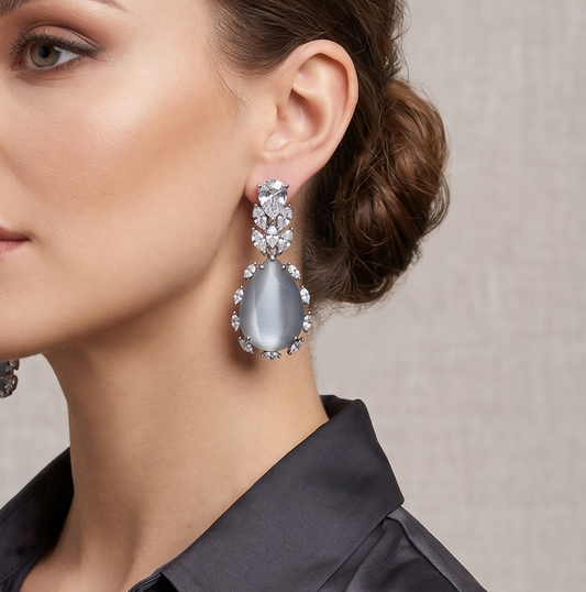 Close-up of a woman wearing a silver earring with a gray gemstone on a neutral background