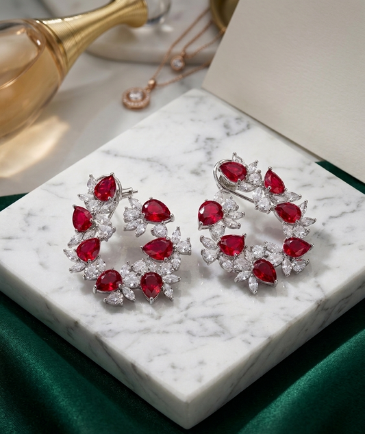 Pair of earrings with red gemstones on a marble surface