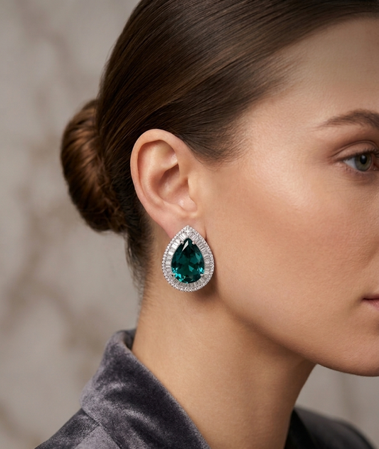 Close-up of a woman wearing a green teardrop earring with a blurred background