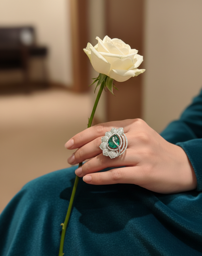 Hand wearing a decorative ring holding a white rose against a blurred indoor background