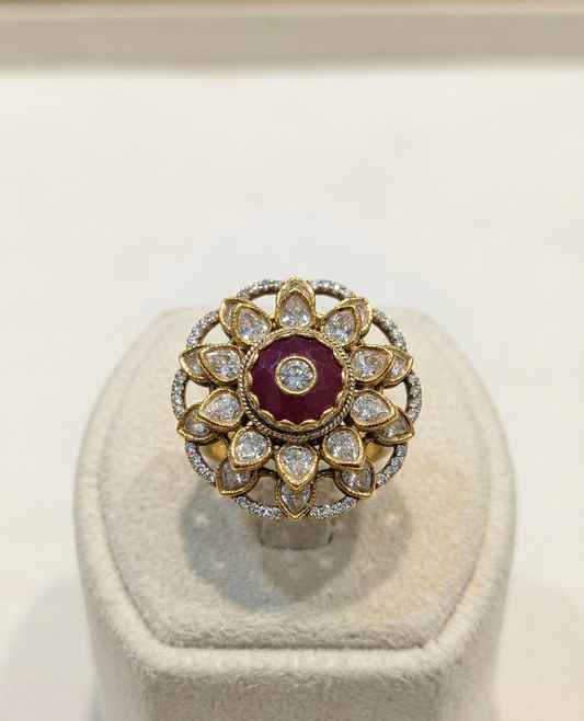 Gold and diamond ring with a red gemstone on a white stand