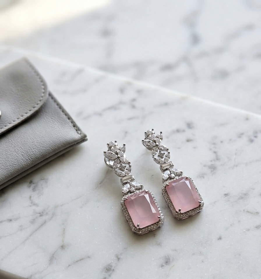 Pink gemstone earrings with silver accents on a marble surface